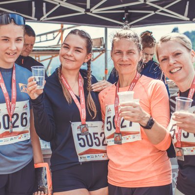 5 km Laufen Vier Teilnehmerinnen mit Medaillen stoßen am Verpflegungsstand beim Stolberger Schloss-Lauf mit Wasser an.